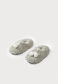 Pantofole grigie morbide e pelose con una finitura a trama soffice. Tra le caratteristiche ci sono due pompon bianchi sulla parte anteriore e un design con retro aperto.