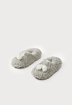 Pantofole grigie morbide e pelose con una finitura a trama soffice. Tra le caratteristiche ci sono due pompon bianchi sulla parte anteriore e un design con retro aperto.