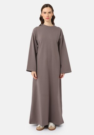 Long, loose-fitting dress made of soft, gray fabric. Features wide sleeves, a round neckline, and reaches the ankles. Paired with white sneakers.