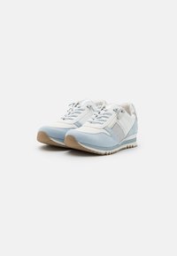 Baskets de sport bleu clair et blanches avec un mélange de cuir et de daim, dotées d'un système de laçage, d'accents argentés et de panneaux latéraux texturés.