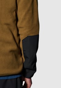 Bruine fleecejack met zwarte nylon accenten op de mouwen. Heeft een gestructureerd oppervlak en een contrasterende blauwe zoomdetail aan de onderkant.
