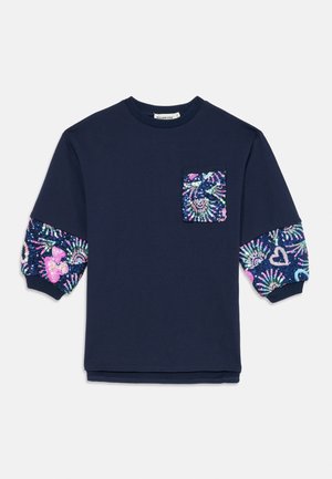 Mørkeblå skjorte med lange ærmer med ribstrikkede manchetter, paliet blomster og hjerte mønstre på ærmer og brystlomme.