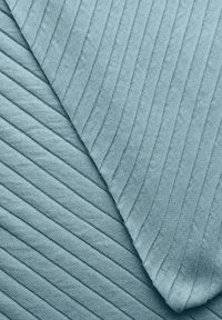 Tissu texturé en bleu clair, présentant des motifs de côtes diagonales et verticales, mettant en valeur une surface douce et moelleuse avec des détails géométriques.