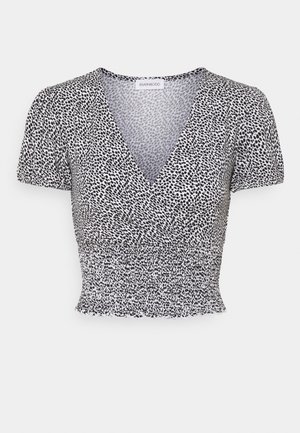 Haut court à manches courtes noir et blanc avec encolure en V, taille froncée et motif all-over de petits pois.