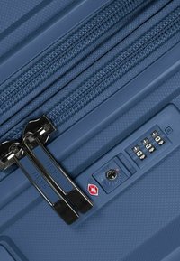Valigia rigida blu con doppie cerniere, superficie testurizzata e lucchetto approvato dalla TSA con combinazione a manopola.