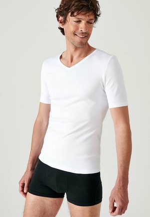 White cotton short-sleeve V-neck t-shirt paired with black boxer shorts. Smooth texture, fitted design, and casual appearance.