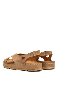 Beżowe skórzane sandały z wyciętym wzorem, regulowanym paskiem i teksturowaną podeszwą. Podwyższona podstawa i przeszycia zwiększają trwałość.