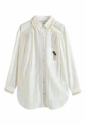 White long-sleeve shirt with gold vertical stripes, zigzag embroidery on collar and cuffs, and a front pocket featuring a black palm tree design.