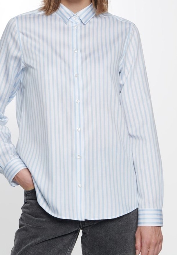 Ljusblå och vit randig skjorta med långt ärm, klassisk krage och knappslutning fram. Har en slät yta.