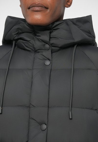 Μαύρο μπουφάν με πλούσια επένδυση και ψηλό γιακά, που διαθέτει μεγάλες ραφές, ρυθμιζόμενο κορδόνι και ματ μαύρους κουμπότρυπες. Λείο, ελαφρύ ύφασμα.