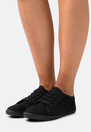 Schwarze Leinensneaker verfügen über ein strukturiertes Seitenpanel und ein traditionelles Schnürdesign. Die Sohle ist aus Gummi und hat eine glatte Oberfläche.