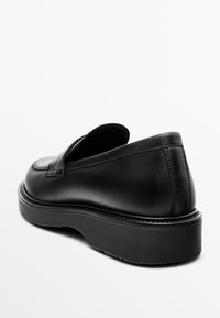 Schwarze Leder-Slipper mit abgerundetem Zeh und einer dicken Gummisohle mit leichtem Plateau, glatter Textur und minimaler Verzierung.