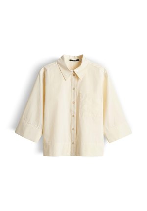 Hemd in cremefarben mit Knöpfen, dreiviertellangen Ärmeln, spitzem Kragen und Brusttasche, auf weißem Hintergrund dargestellt.