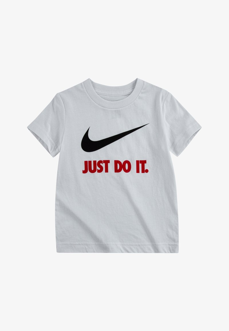 Maglietta in cotone bianco con un grande logo Nike swoosh nero e testo rosso che recita "JUST DO IT" sul fronte. Maniche corte, scollatura rotonda.