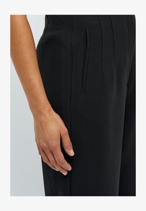 Zwarte op maat gemaakte pantalons met een zachte textuur. Bevat zijzakken en een vlakke voorkant, accentueerd door subtiele stiksels.