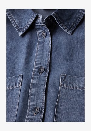 Denim shirt in een donkere blauwe kleur, met een button-down kraag, twee vo Taschen en contrasterende stiksels langs de randen. Gladde textuur.