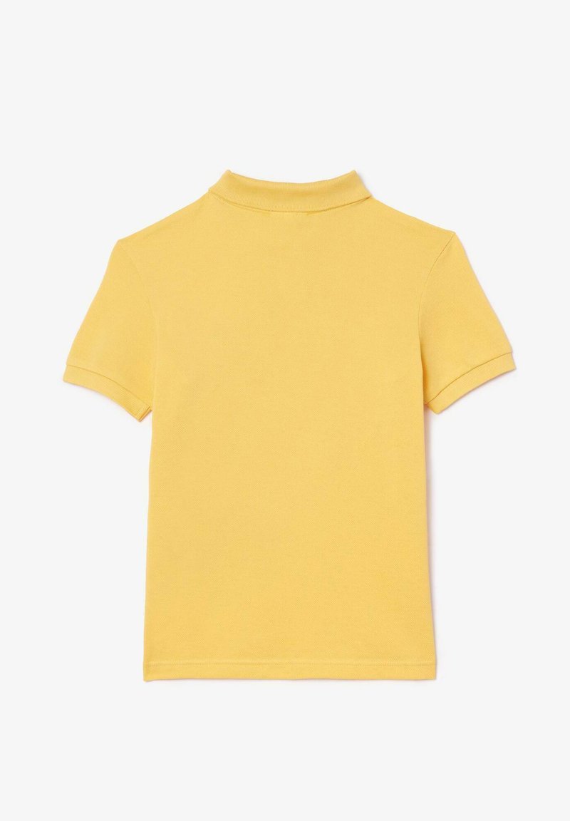 Polo shirt jaune à manches courtes avec col, fabriqué en tissu texturé, comportant des détails de ourlet cousu et un design épuré et minimal.