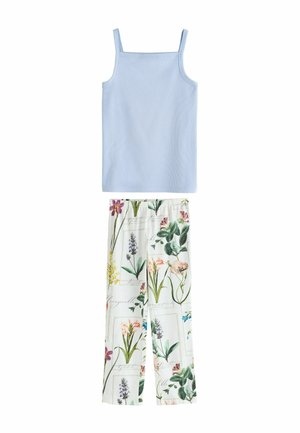 Lichtblauwe mouwloze top gecombineerd met witte broek met een kleurrijke botanische bloemen- en bladmprint.