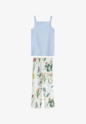 Caraco bleu clair sans manches associé à un pantalon blanc avec un imprimé floral et feuillage botanique coloré.