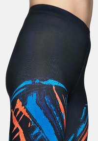 Zwarte leggings met abstracte patronen in blauw en oranje, gemaakt van een rekbare, gladde stof met een aansluitende silhoeët.