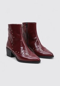 Bottines en cuir bordeaux à bouts pointus, ornées de clous en argent et d'un design cousu, avec une fermeture éclair sur le côté et un talon bloc.