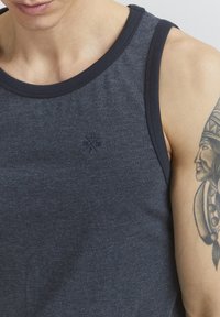 Marineblaue Tanktop aus weichem Baumwollmaterial, mit einem Rundhalsausschnitt und einem dezenten gestickten Logo auf der Brust. Sanfte Textur.