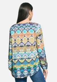 Kolorowa bluzka z długim rękawem z geometrycznym wzorem w odcieniach niebieskiego, zielonego i pomarańczowego; przezroczysta tkanina o luźnym kroju.