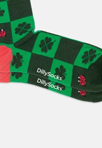 Grønne og sorte ternede sokker med kløver- og mariehøne-mønstre, der har en koralfarvet hæl og 'DillySocks'-branding.