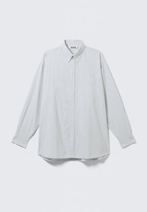 Chemise blanche à manches longues boutonnée avec fines rayures noires verticales et poche poitrine, présentée à plat sur un fond clair.