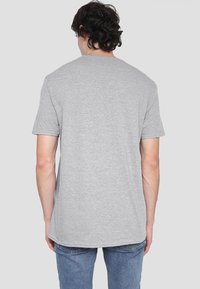 Gray short-sleeve t-shirt, round neckline, soft texture, relaxed fit, cotton blend, no visible patterns, denim jeans visible below.