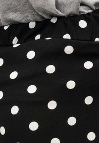 Μαύρο ύφασμα με λευκά πουά δίπλα σε γκρι πλεκτό ύφασμα, που δείχνει την αντίθεση υφής και μοτίβου σε κοντινή άποψη.