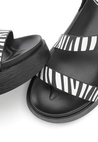 Black platform sandals featuring two wide straps with a zebra print pattern. The material is a combination of smooth and textured surfaces.