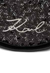 Black sequined bag featuring a silver "Karl" logo, with a textured surface, glossy finish, and circular sequin patterns on the fabric.