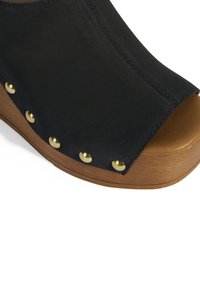 Schwarze offene Keil sanda mit einem Wildleder-Obermaterial, Holzohr und goldfarbenen Nieten entlang der Kante. Glatte Textur mit abgerundeter Form.