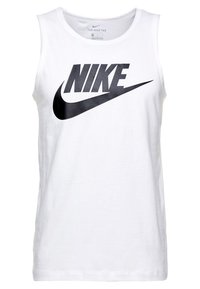 Bela bomba iz bombaža z velikim črnim logotipom Nike na sprednji strani. Oblikovanje vključuje okroglo ovratnico in brezrokavni kroj.