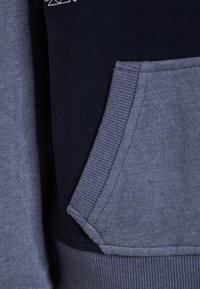 Donkerblauwe en grijze hoodie met een kangoeroezak, ribgebreide manchetten en een zachte textuur met contrasterende stofpanelen.