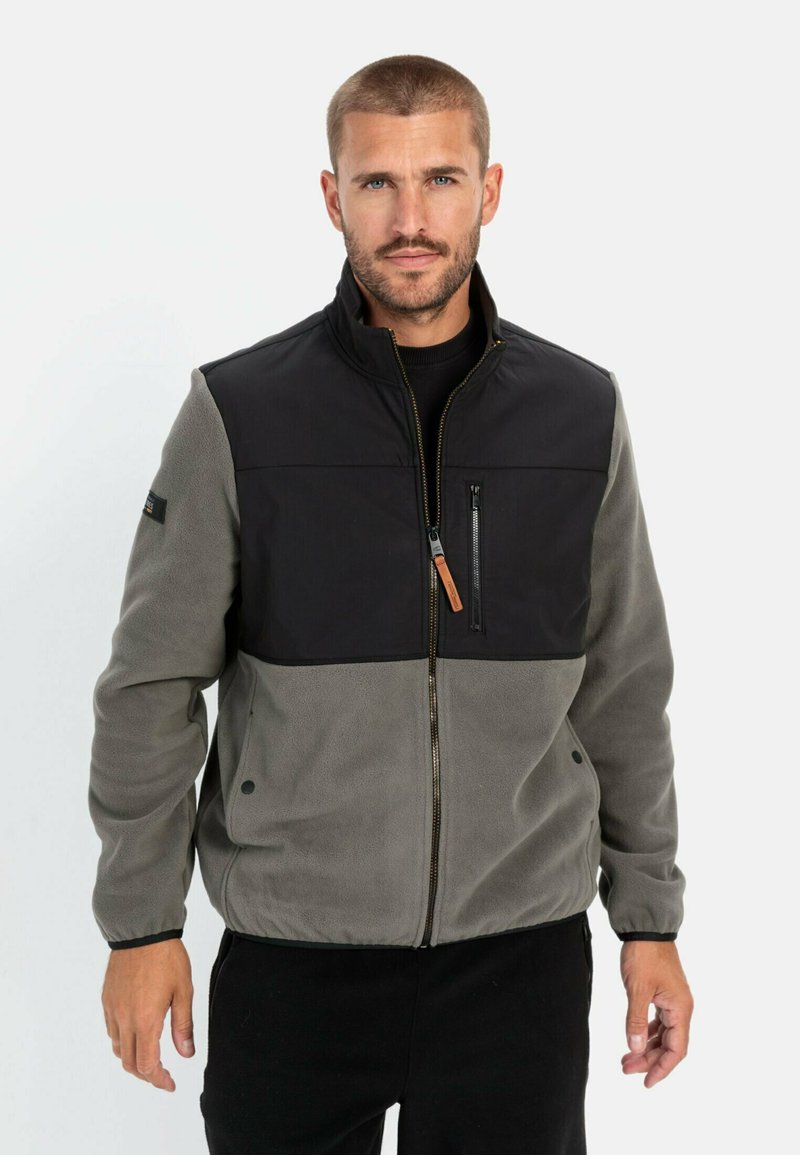 Fleecejacke mit schwarzem Oberteil und grauem Unterteil, ausgestattet mit einer Reißverschlusstasche auf der Brust, Reißverschluss und verstellbaren Bündchen.