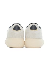 Grijze nubuck sneakers met zwarte accenten, een gestructureerde achterkant en een crême rubberen zool. Achteraanzicht, met contrasterende stikdetails.