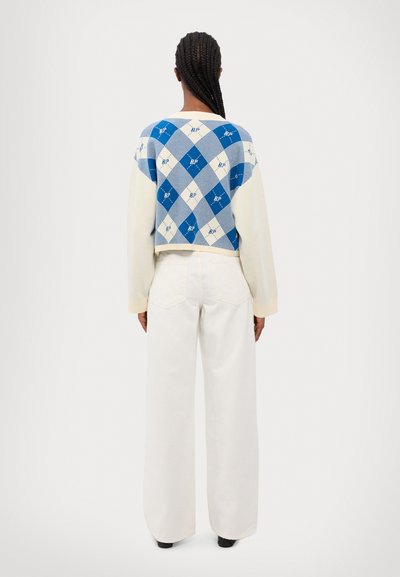Blue and white argyle-patterned cropped sweater with long cream sleeves, paired with wide-leg white trousers. Simple design, casual textures.