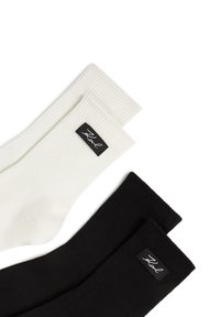 Prążkowane bawełniane skarpetki w kolorze białym i czarnym. Każda para ma czarną metkę z białym napisem na górze. Miękka tekstura o casualowym designie.