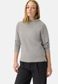 Pull gris à côtes avec capuche, doté de manches longues et d'une coupe décontractée. Associé à un pantalon sombre et à un petit logo brodé au bas.