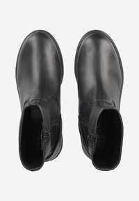Bottes noires en cuir au niveau de la cheville avec une texture lisse et une fermeture éclair sur le côté. Dotées d'un bout rond et d'une semelle plate. Design minimaliste sans embellissements.