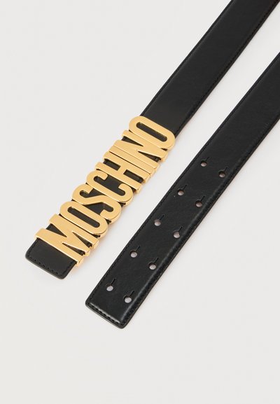 Μαύρη δερμάτινη ζώνη με πολλαπλές τρύπες και μεγάλα χρυσά γράμματα που σχηματίζουν τη λέξη «MOSCHINO» ως αγκράφα σε λευκό φόντο.