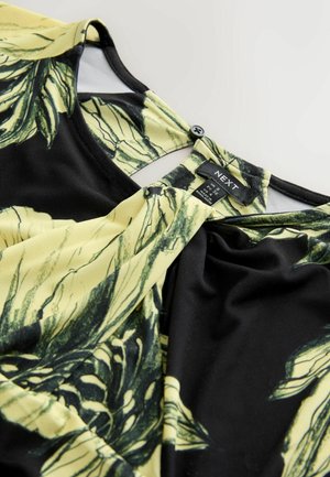 Mustast tipp, millel on kollased lillemustrid. Valmistatud siledast kangast, millel on tagaküljel nööbikinnitus ja pehmed voltimismehhanismid.