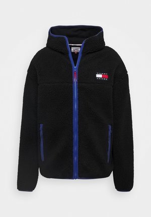 Zwart fleecejack met blauwe rits en zakken, hoge kraag en Tommy Jeans-logo op de borst.