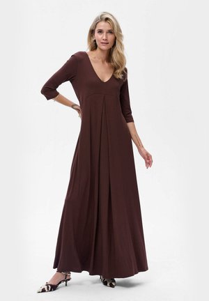 Robe longue marron avec un décolleté en V, des manches trois-quarts, un devant plissé et un tissu doux. Accompagnée de chaussures à bout pointu ornées d'un motif vache.