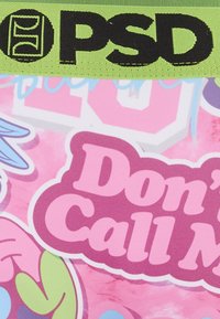 Ceinture verte vif avec le logo "PSD" au-dessus d'un tissu rose orné de motifs colorés et de textes, y compris "Don't Call Me".