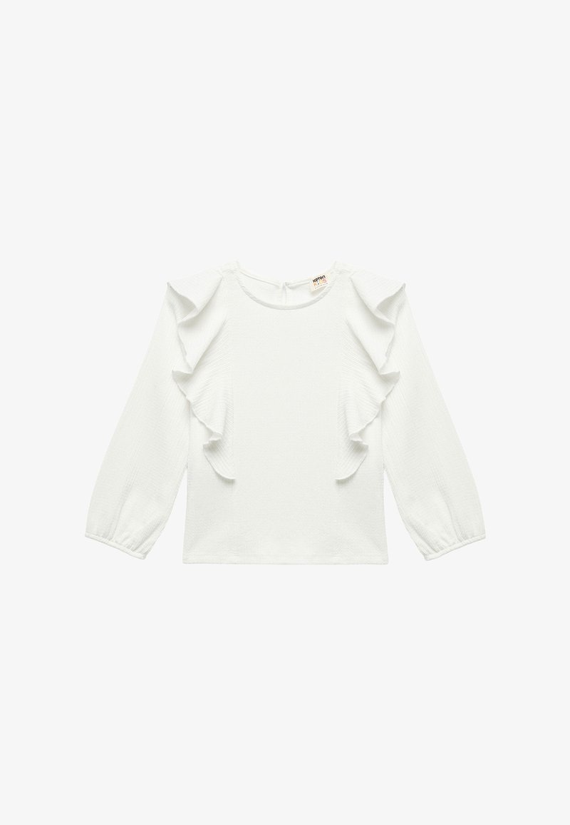 Hvid langærmet top med flæser ved skuldrene og ærmerne. Fremstillet af struktureret stof, med rund halsudskæring og lukning i ryggen.