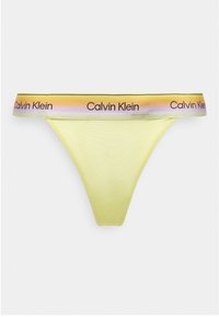 Κίτρινο εσώρουχο τύπου thong με ζώνη μέσης σε ουράνιο τόξο, με επαναλαμβανόμενα λογότυπα "Calvin Klein" σε μαύρο κείμενο.