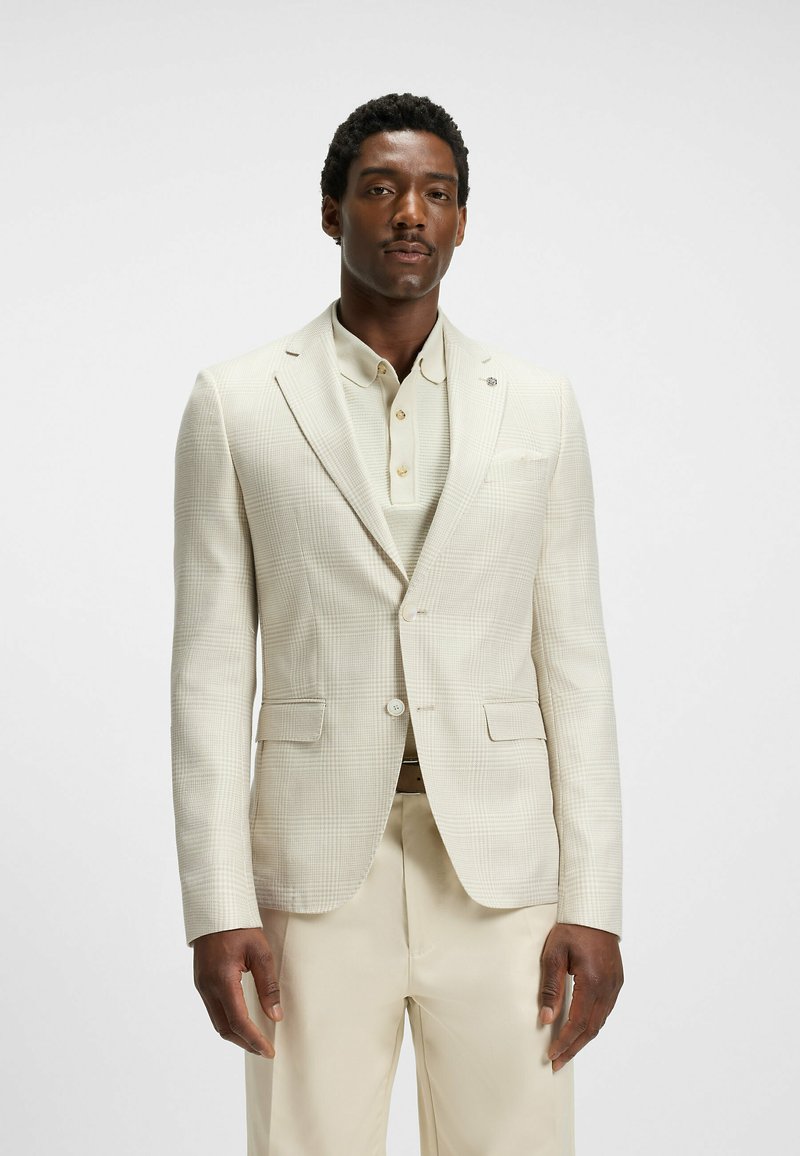 Helles beige Blazer mit dezentem Karomuster, Ein-Knopf-Verschluss, Reverskragen und zwei Fronttaschen, kombiniert mit einem hellen Hemd.
